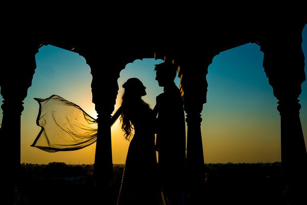 A silhouette shot taken during sunset, capturing the outlines of the couple against the beautiful sky, creating a romantic and timeless image. 